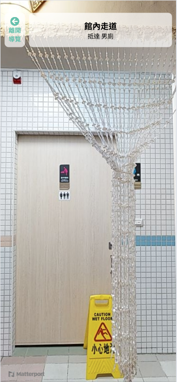 虛擬空間中抵達廁所入口，畫面上方有前往男廁的導航提示。